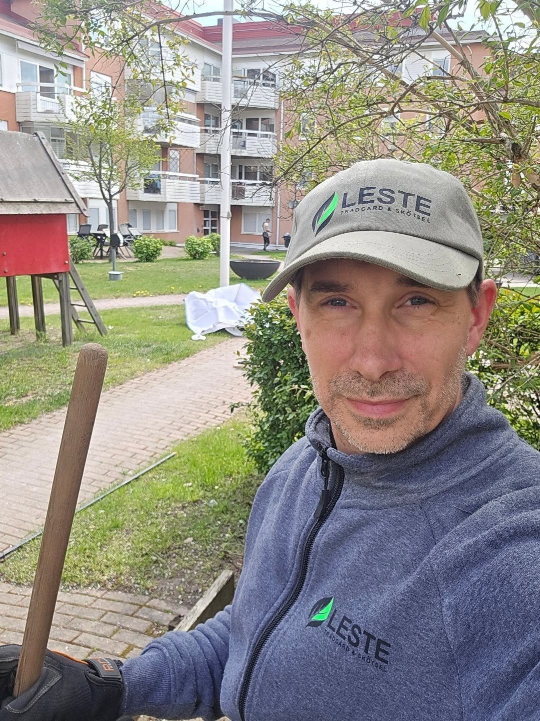 en anställd close up med redskap i hand och en brf i bakgrunden